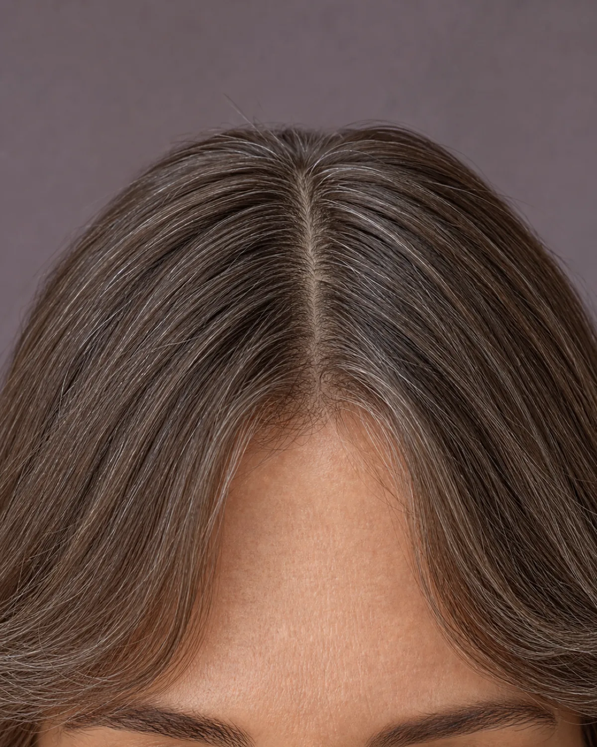 A close crop of a woman's forehead and centre parted curtain fringe, the shortest point at the brow and the longest pieces sweeping down toward her cheekbones